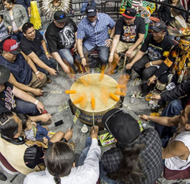 Native Americans gathered around a ceremonial drum during a pow wow.