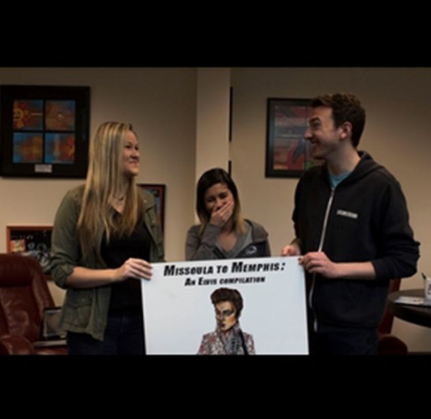 students sharing a laugh while holding up a sign to promote a concert.