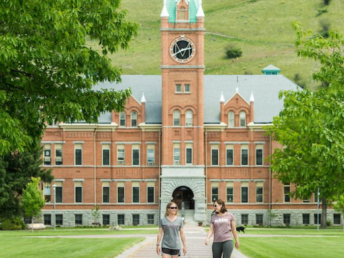 two students walking away from UM main hall