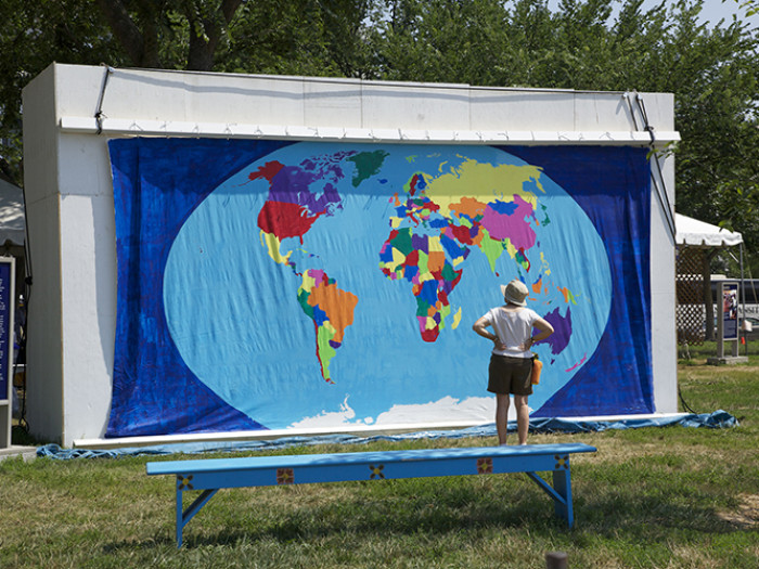 person looking at a large painted world map displayed outside