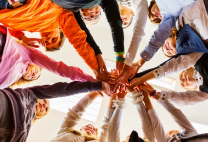 Kids in a circles with their hands all in the center
