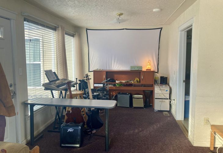 Photo of music equipment in the I-House. Item include amps, electric and acoustic guitars, electric drum set, and a keyboard