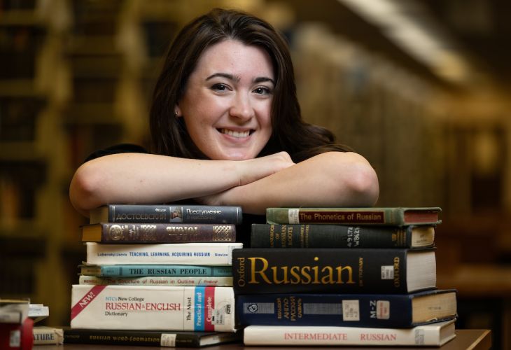 UM student sitting at table with a stack of books