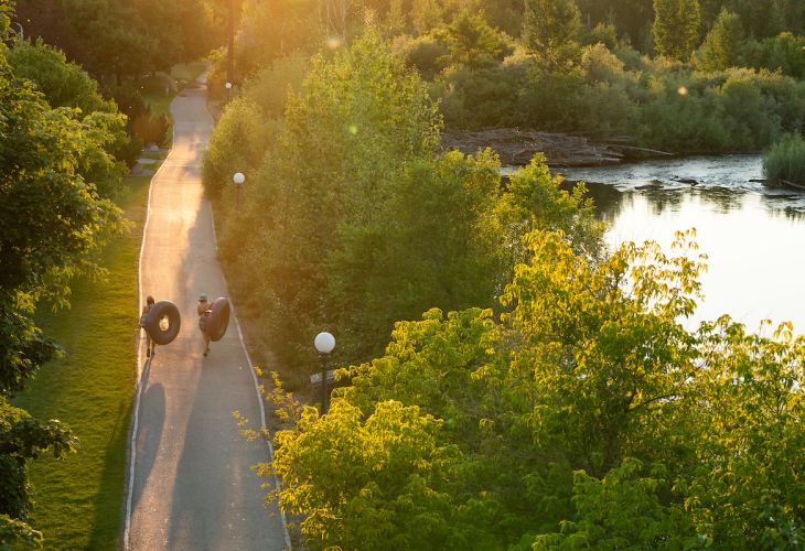 Two UM students walking down river trail with tubes