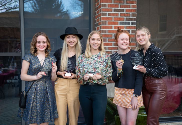 DHC students holding Evening of Excellence awards on the DHC patio