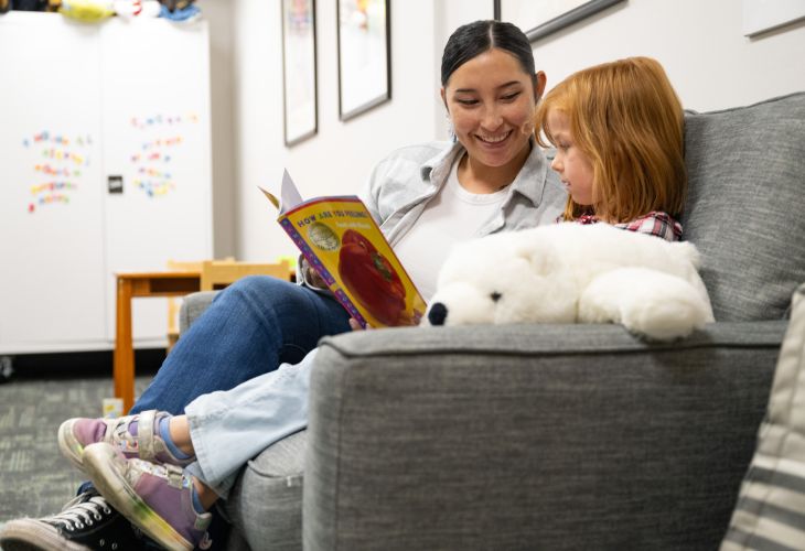 A UM School Psychology clinician reading "How Are You Feeling" with a child