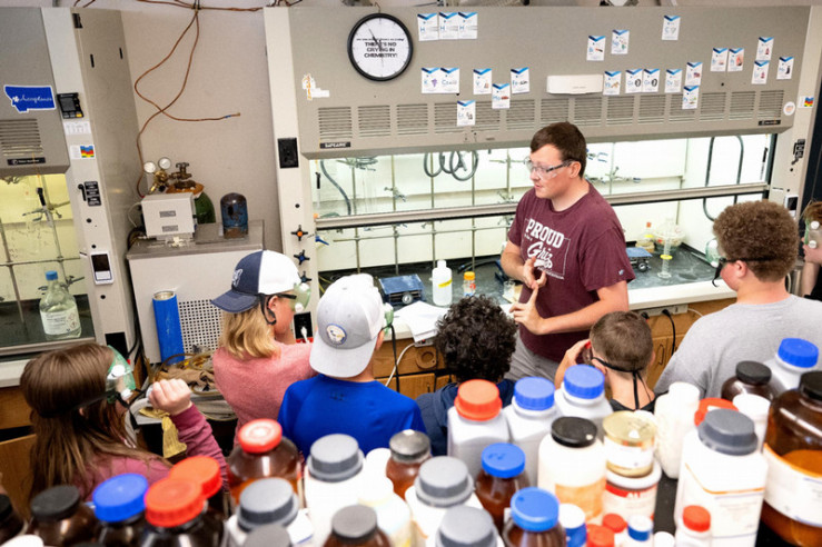 A graduate student demonstrates a reaction for a group of 6th grade students.