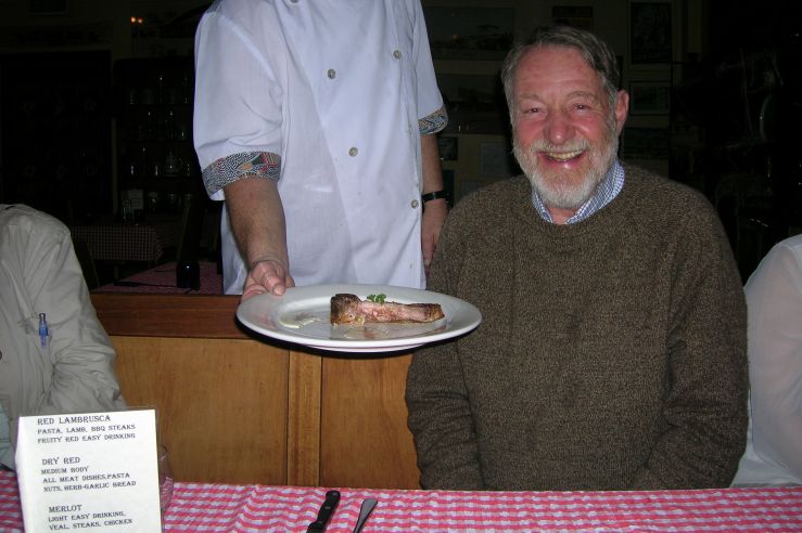 Don smiles while a waiter hands a plate with food.