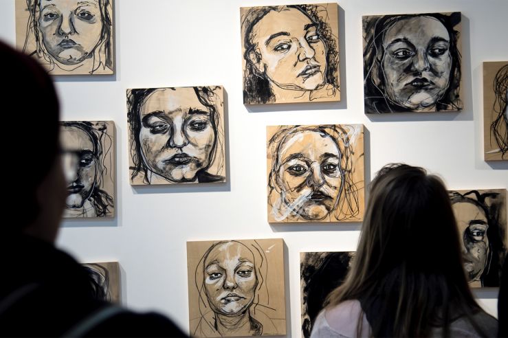 People observing portraits on a UC Gallery wall