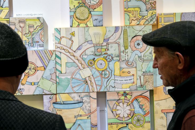Two men admiring some intricate and colorful Dr. Seuss-like drawings