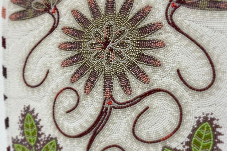 closeup of beadwork in purple, green, and ivory of a bitterroot flower