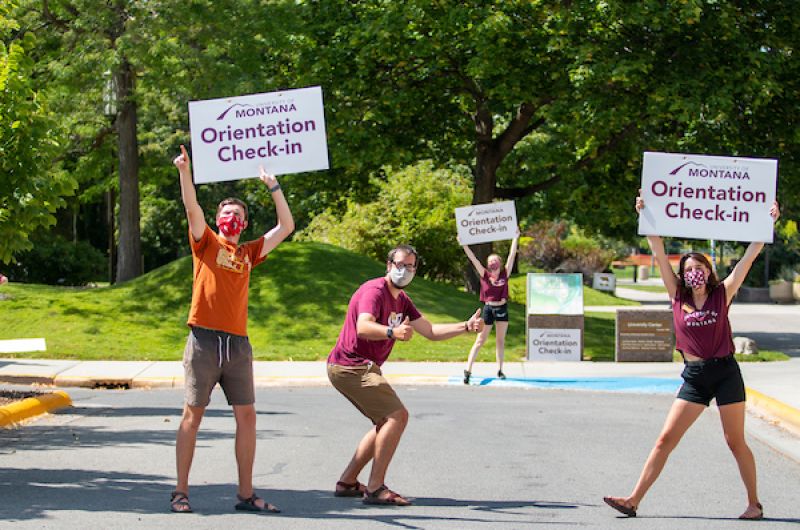 Three Advocates hold Orientation Check In signs
