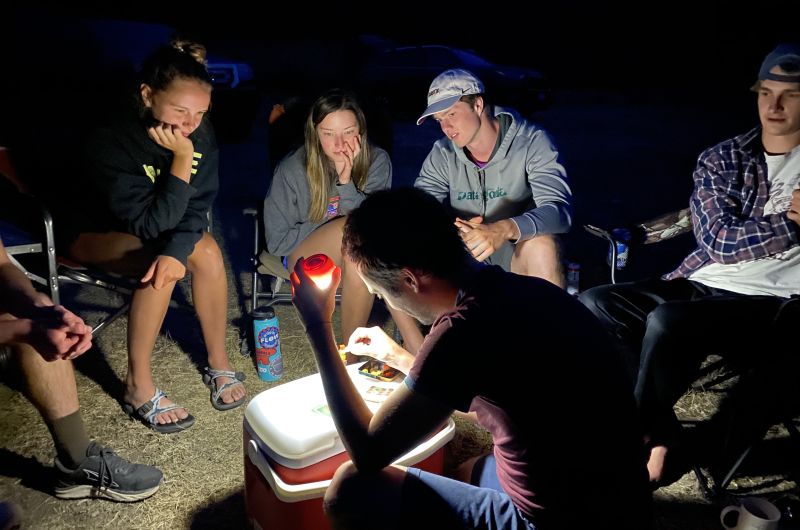 Grad students in the field at night gathered around a flashlight.