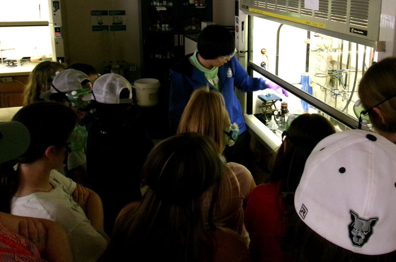 A graduate student demonstrates a reaction to a group of students,