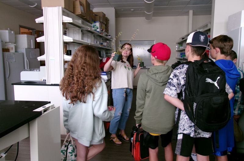 A graduate student shows some students an ecology research lab.