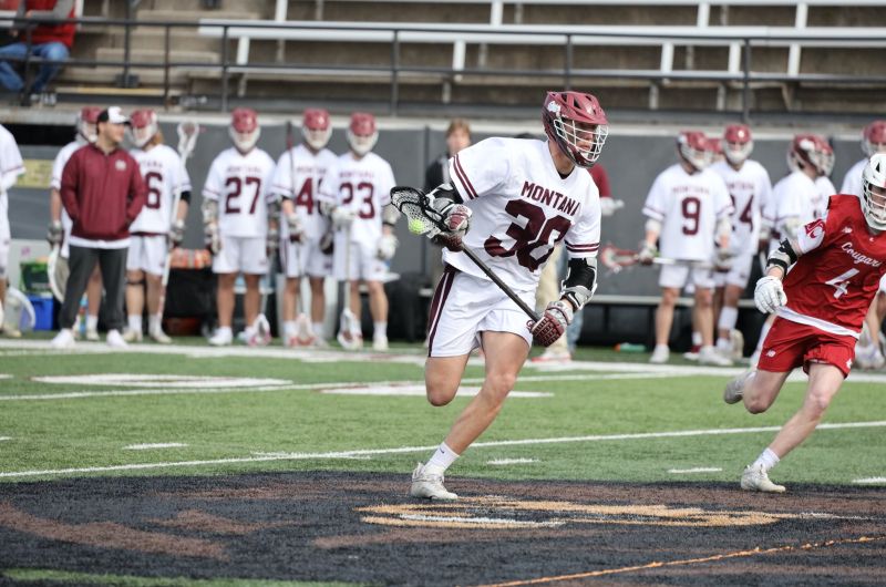 A Griz Lacrosse player running with the ball during a home game against Washington State