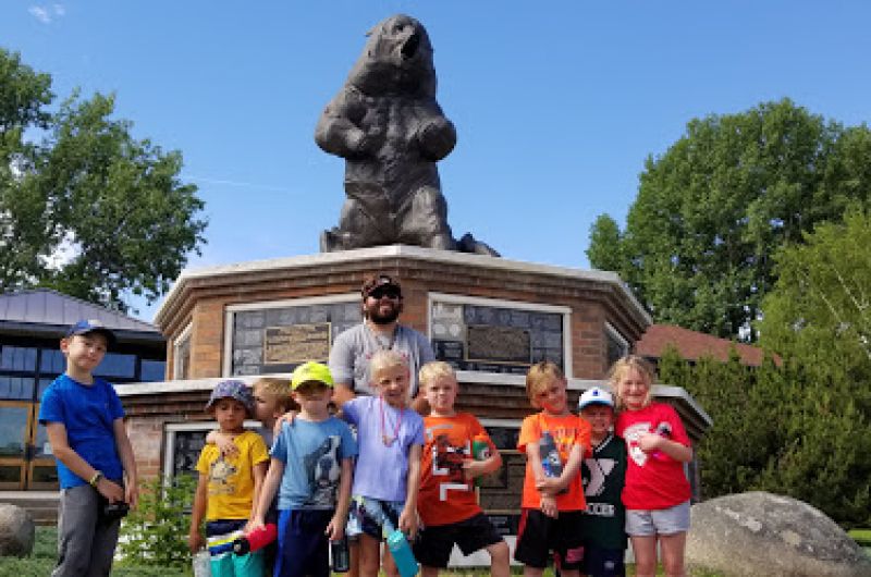 Children and guardian posing in front of a bear statue