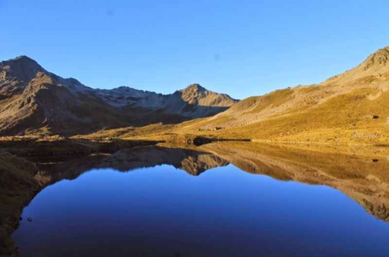 A view of a glistening lake surrounded by small mountains in New Zealand