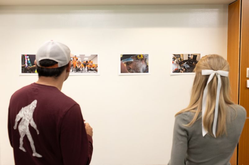 People hang photography in a gallery.