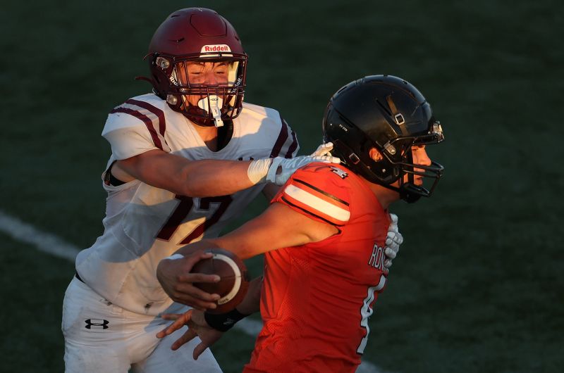 Football players in helmets spar on the field. 