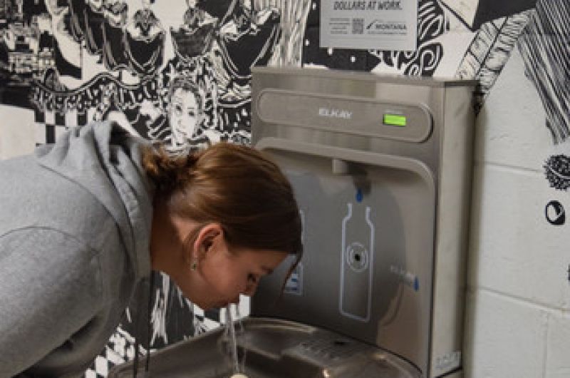 zoe sips water from a water bottle station in the fine arts building