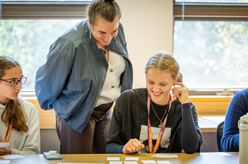 A teacher standing over a student looking at flash cards