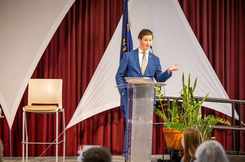 A student standing up on stage speaking to other students