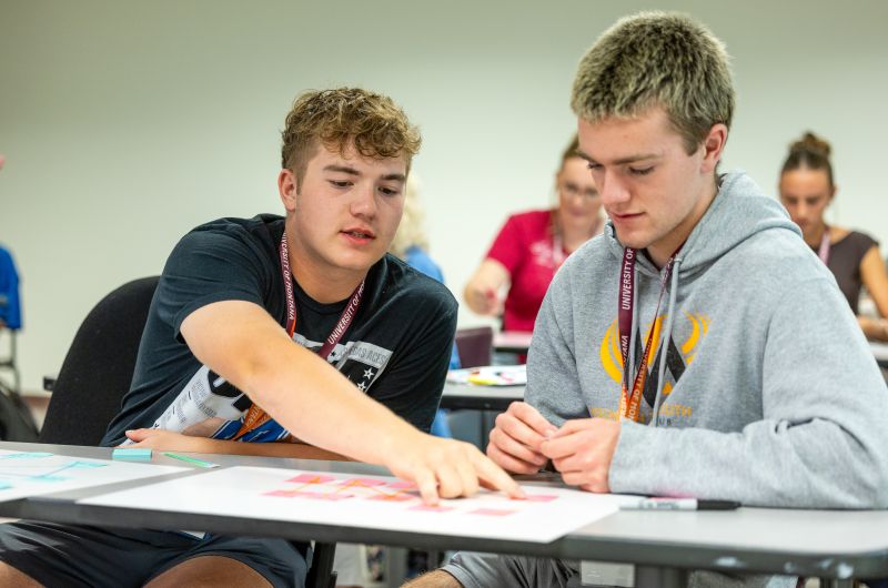 A student showing another student something on paper.