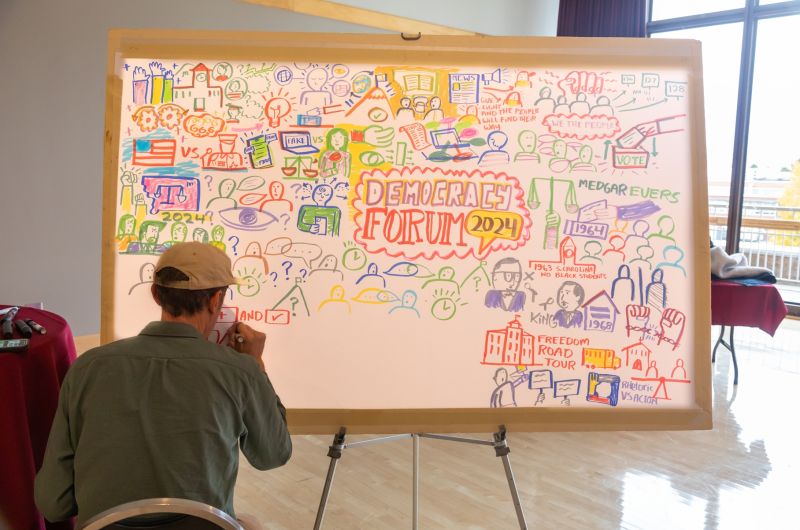 A student filling out a democracy forum poster