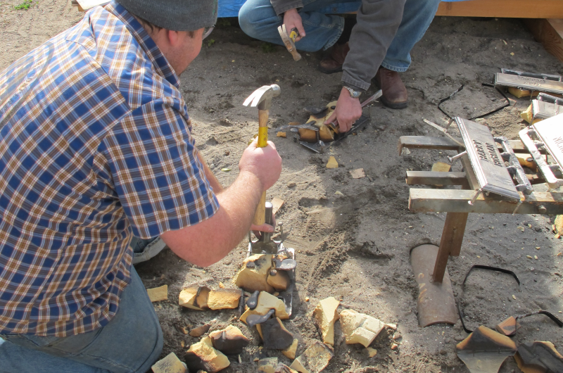 Allen chisels a newly-cast marker out of its sand mold.