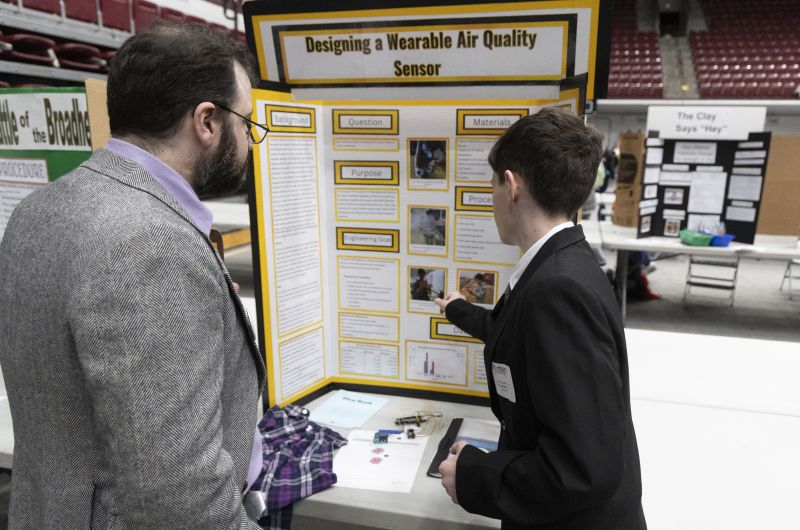 student pointing at their poster board