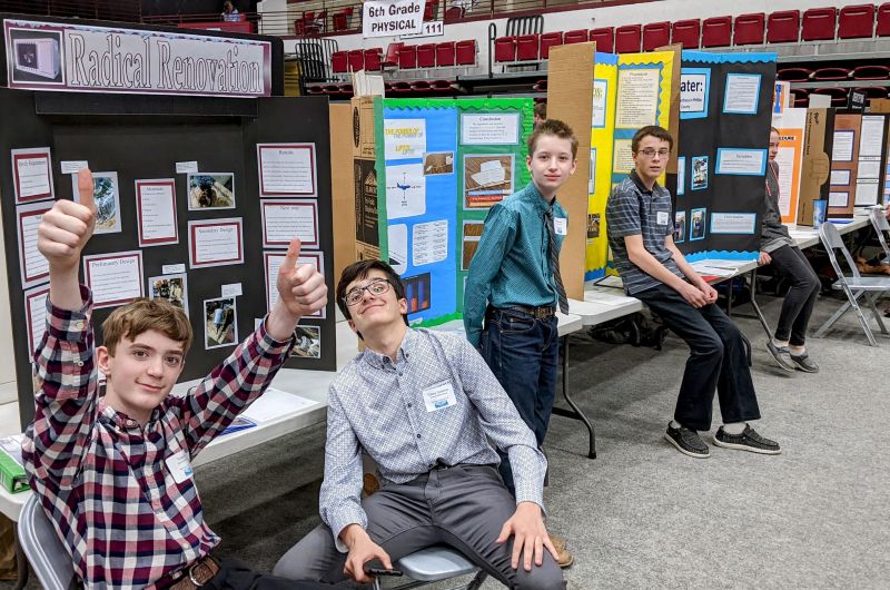 kids smiling at the science fair sitting down