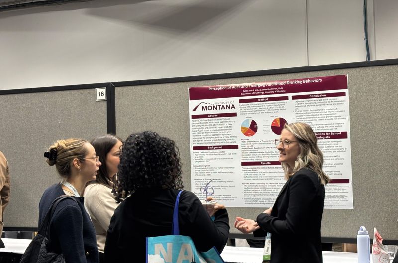 A graduate student pointing at her conference poster, explaining to three conference atendees