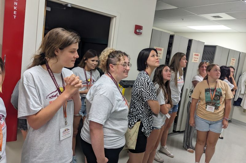 A group of students look up at a display out of frame