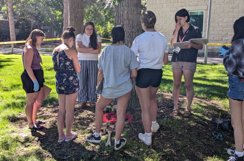 Professor Snow discusses the "mock remains" found on the ground with a group of students.
