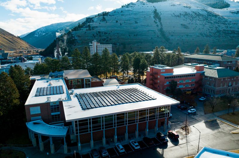 drone shot of the top of education building's solar panels with mount sentinel in the background