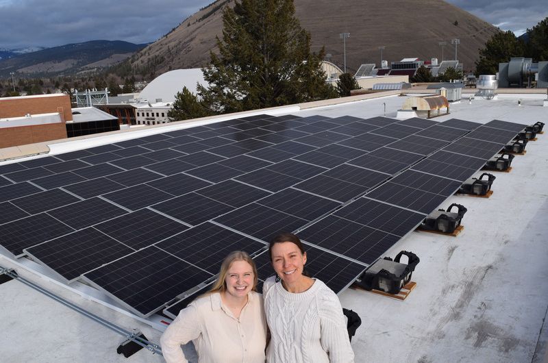 eva and tayli smile in front of the education building solar array