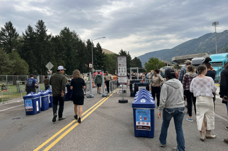 blue recycling bins lined up outside the gates as people enter the stadium.