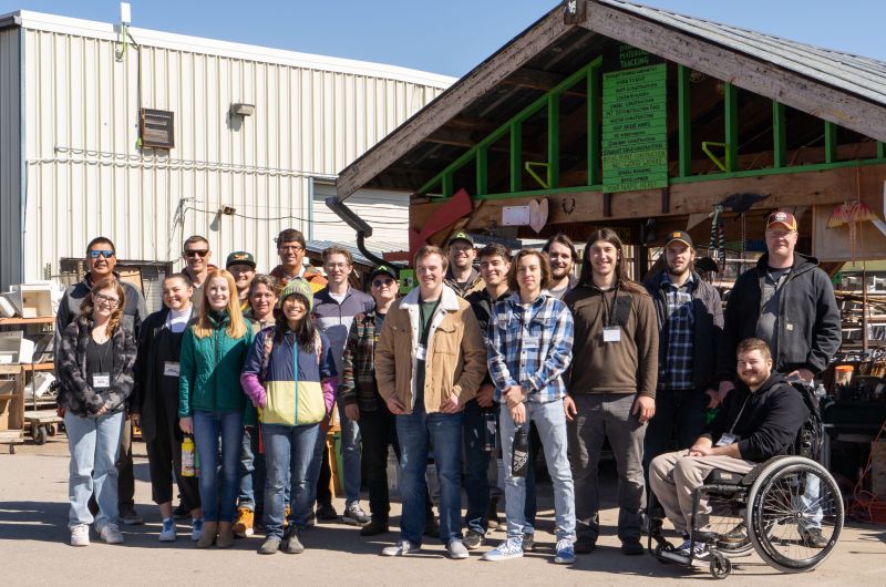 a large group of students poses outside a workshop as part of the ATG cognizant spring break