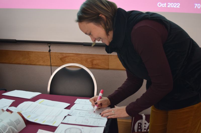 an employee is smiling as they write something down with a pink marker