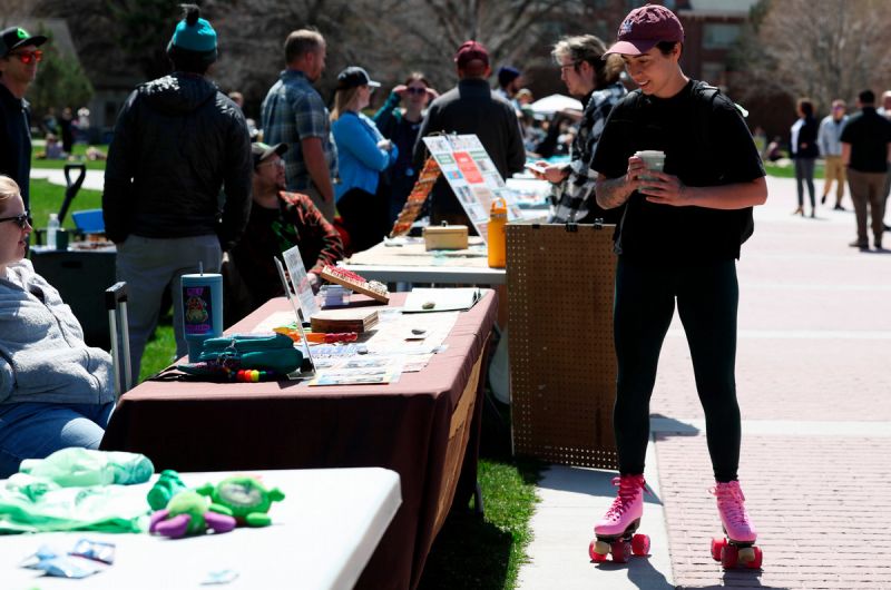 a student on roller skates pausing at tables at the sustainability fair