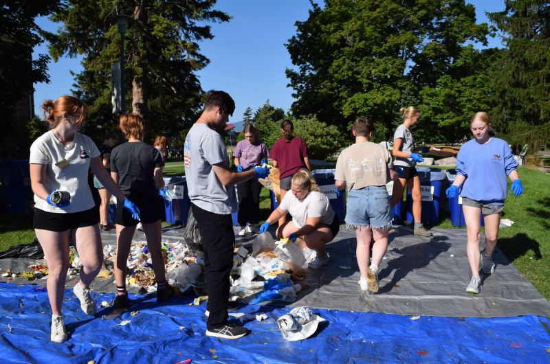 students help sort trash on the lawn of the UC