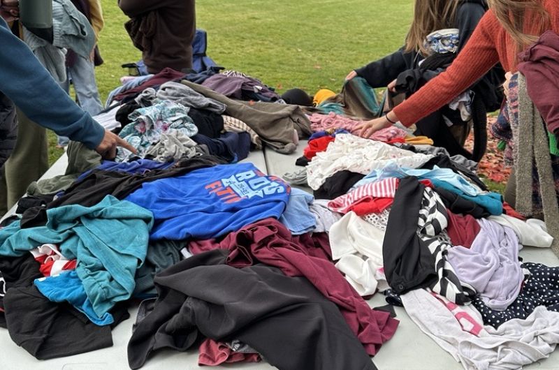 people sort through a giant pile of clothes at the clothing swap