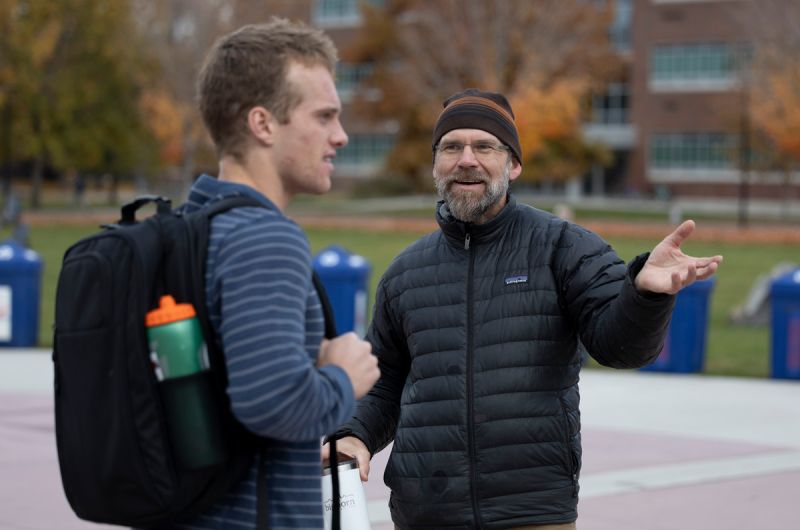 derek educates a man about the zw demonstration with recycle bins in the back