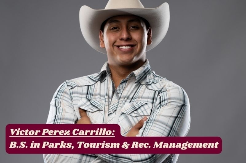 Victor grins at camera with arms folded, white cowboy hat tipped back