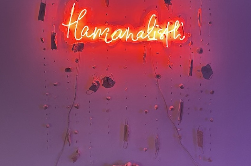 neon and ceramic installation artwork, neon says 'tlamanalistli' with ceramic masks and skulls