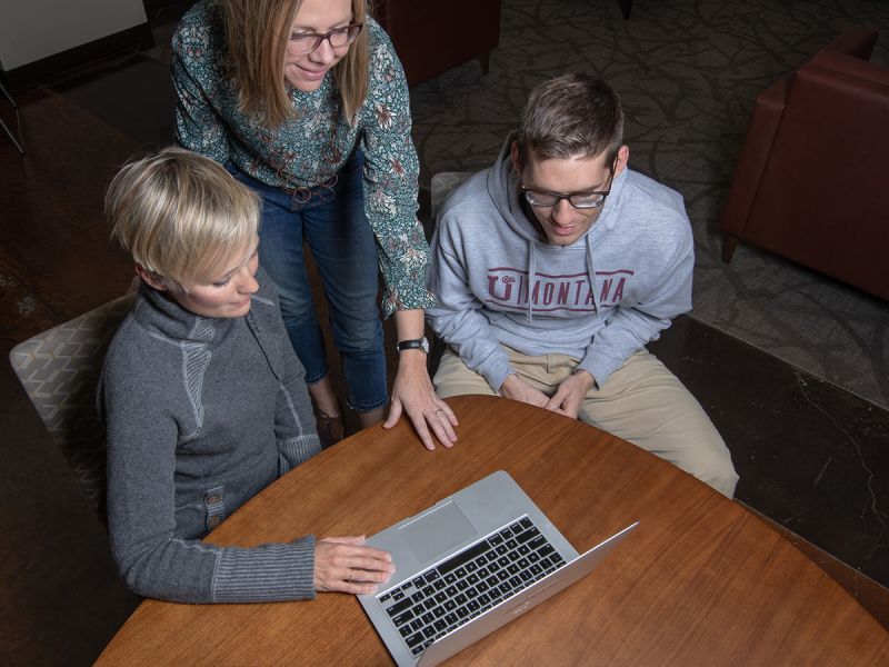 MBA students and professor, gathered around a computer.