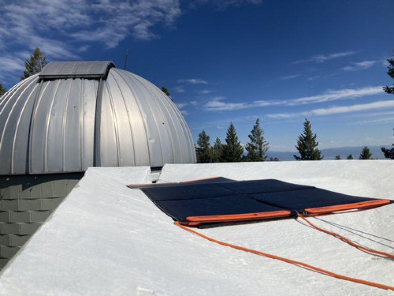 an orange and black solar panel with the observatory in the background