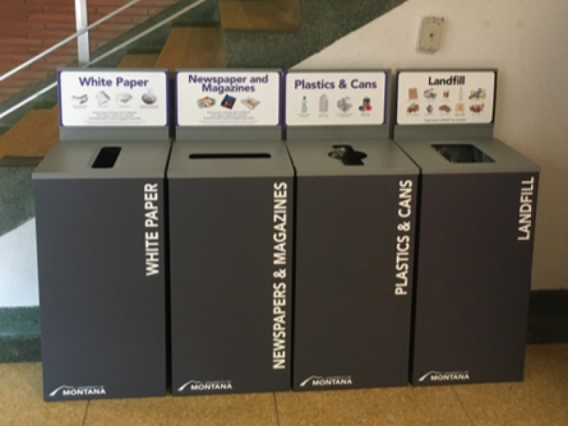 a row of gray bins with labeled recycling streams