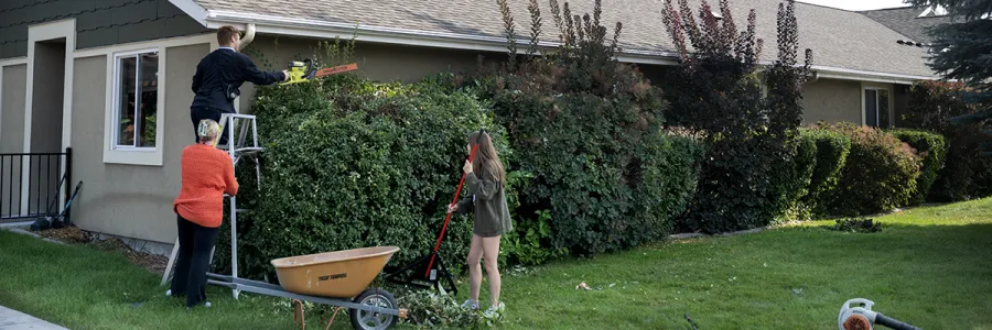 Students participate in a volunteer event cleaning outside a house 